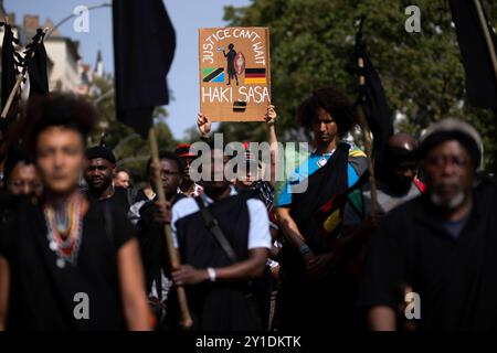 Gedenkmarsch und Strassenumbenennung Afrikanische Viertel DEU, Deutschland, Germania, Berlino, 23.08.2024 Demonstranten der Diaspora mit Plakat Justice Cant Wait Haki Sasa und Fahne von Tansania beim Gedenkmarsch und der Zeremonie Strassenumbenennung der Petersallee in Die Maji-Maji-Allee und die Anna-Mungunda Die Umbennung geht auf Die Initiative Decolonize the City zurueck und erinnert an die Verbrechen der deutschen Kolonialherrsch Foto Stock