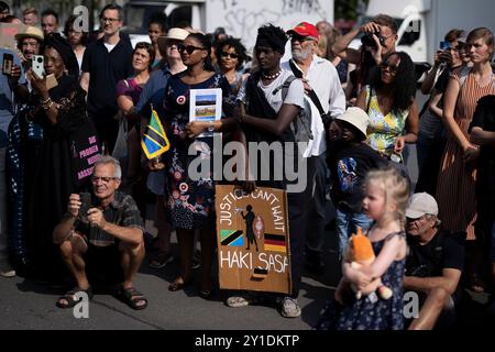 Gedenkmarsch und Strassenumbenennung Afrikanische Viertel DEU, Deutschland, Germania, Berlino, 23.08.2024 Demonstranten der Diaspora mit Plakat Justice Cant Wait Haki Sasa und Fahne von Tansania beim Gedenkmarsch und der Zeremonie Strassenumbenennung der Petersallee in Die Maji-Maji-Allee und die Anna-Mungunda Die Umbennung geht auf Die Initiative Decolonize the City zurueck und erinnert an die Verbrechen der deutschen Kolonialherrsch Foto Stock