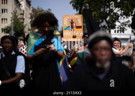 Gedenkmarsch und Strassenumbenennung Afrikanische Viertel DEU, Deutschland, Germania, Berlino, 23.08.2024 Demonstranten der Diaspora mit Plakat Justice Cant Wait Haki Sasa und Fahne von Tansania beim Gedenkmarsch und der Zeremonie Strassenumbenennung der Petersallee in Die Maji-Maji-Allee und die Anna-Mungunda Die Umbennung geht auf Die Initiative Decolonize the City zurueck und erinnert an die Verbrechen der deutschen Kolonialherrsch Foto Stock