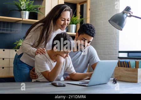 Felice famiglia multietnica. Genitori di razza mista che aiutano adolescenti a scuola a casa. Foto Stock