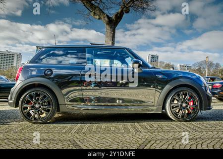 Lisbona, Portogallo - 20 gennaio 2024: Vista laterale dell'elegante Mini John Cooper Works completamente nera parcheggiata su un sentiero acciottolato vicino al parco verde nelle giornate di sole. Foto Stock