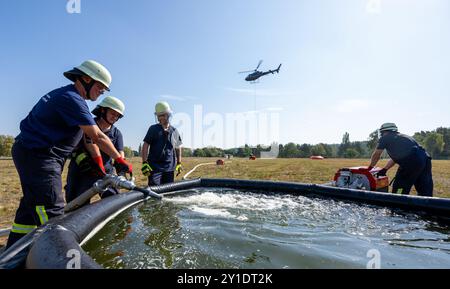 Bleckede, Germania. 6 settembre 2024. Durante un'esercitazione antincendio forestale, i vigili del fuoco volontari riempiono una cisterna d'acqua estinguente dalla quale gli elicotteri antincendio vengono riempiti tramite un condotto. I vigili del fuoco volontari del dipartimento dei vigili del fuoco della bassa Sassonia hanno praticato l'uso di due elicotteri per combattere gli incendi di vegetazione. Crediti: Philipp Schulze/dpa/Alamy Live News Foto Stock