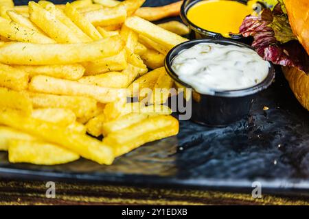 Hamburger con patatine fritte e due tipi di salsa a lato, vista ravvicinata delle patatine fritte su un piatto Foto Stock