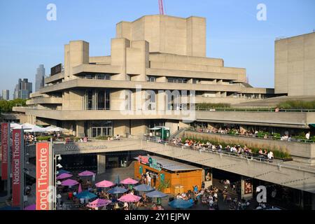 Persone che si godono un drink serale sulle terrazze del Teatro Nazionale. Il National Theatre fa parte del Southbank Centre. Il teatro era progettato Foto Stock