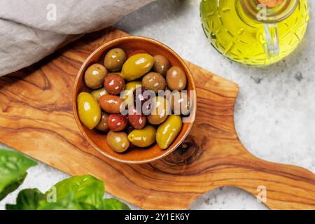 Un assortimento di olive varie presentate in una ciotola e in una bottiglia di olio d'oliva, mostrando colori, consistenze e sapori diversi Foto Stock