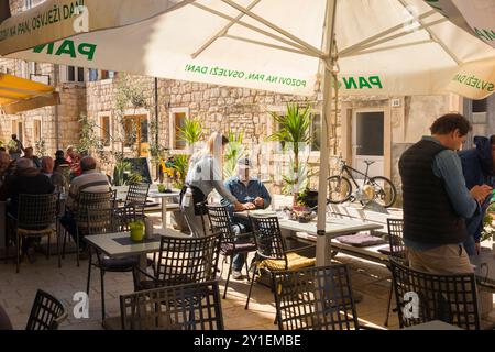 Tavoli all'aperto con ombrelloni per ombrelloni e cene al Restoran Marko / Marko's Pizzeria & Spaghetteria. Ristorante Marko, pizzeria che serve anche pasta, a Stari Grad, isola di Hvar, Croazia. (138) Foto Stock