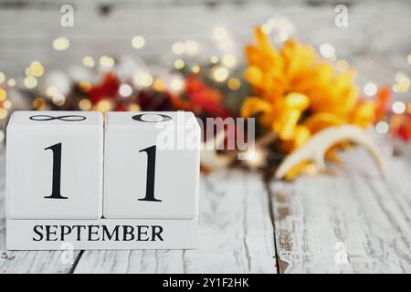 Blocchi di calendario in legno bianco con la data dell'11 settembre e decorazioni autunnali su un tavolo di legno. Messa a fuoco selettiva con sfondo sfocato. Patriot D. Foto Stock