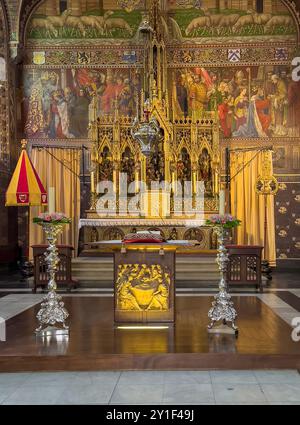 Bruges, Fiandre, Belgio - 25 giugno 2024: Basilica del Santo sangue altare maggiore in primo piano e parte di reredos dorati pieni di dipinti Foto Stock