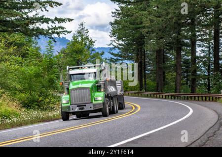 Trattore semi-autocarro con cassone ribaltabile per trasporto locale verde per impieghi industriali con due rimorchi ribaltabili per il trasporto di carichi in movimento sulle montagne tortuose Foto Stock