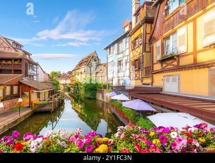 Pittoreschi e colorati edifici in legno con caffetterie sul lungomare lungo il fiume Lauch e il canale nella storica Petite Venise Colmar, Francia medievale. Foto Stock