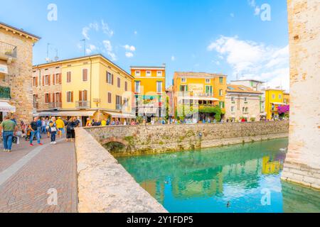 I visitatori potranno visitare i negozi e le caffetterie di Piazza Castello all'esterno del Castello Scaligero, nella località turistica sul lago di Sirmione, in Italia. Foto Stock