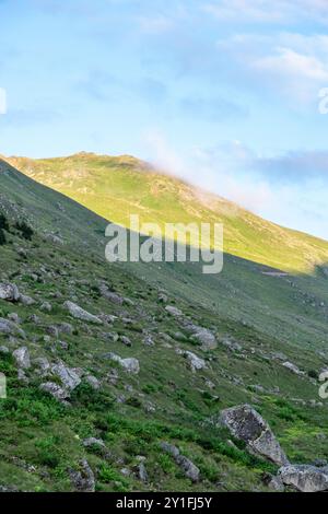 Le pendici illuminate dal sole dell'altopiano di Amaklit a Camlihemsin, con rocce aspre e vegetazione lussureggiante, offrono una vista mozzafiato della natura incontaminata e del tranqu Foto Stock