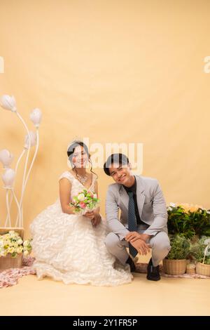 le coppie di uomini e donne sedute sedute in posa rilassata sorridono l'un l'altro guardando avanti intimamente foto in interni. studio nazionale di sposa per matrimoni di coppia Foto Stock