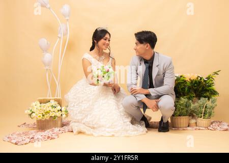 coppia di uomini e donne posa seduti a guardarsi l'un l'altro intimamente in interni. studio nazionale di sposa per matrimoni di coppia Foto Stock