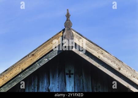 Cresta del tetto su una vecchia casa in legno con falegnameria e una croce sul timpano Foto Stock