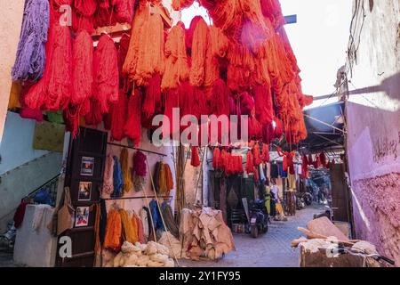 Fili di tessuto di colore rosso appesi ad asciugare per la vendita in un suk di Marrakech in Marocco Foto Stock