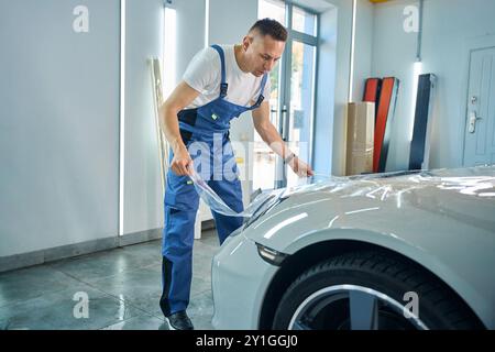 Processo di incollaggio della pellicola protettiva sull'auto nel centro di assistenza auto Foto Stock