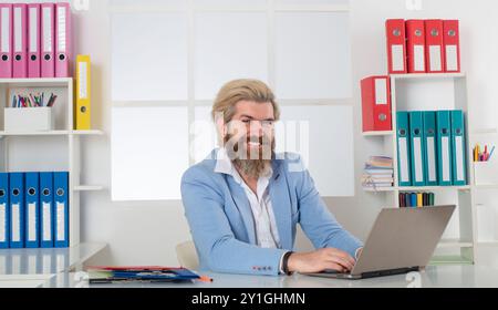 Happy Business man che lavora con pile di documenti cartacei. Ricerca di informazioni. Documenti di report e pile di documenti ottenuti sulla scrivania del computer portatile Foto Stock