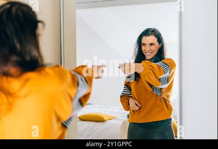 Una donna single sicura di sé che punta il dito al riflesso nello specchio che balla e abbatte bene. Una persona indipendente con un'alta autostima parla positivo Foto Stock
