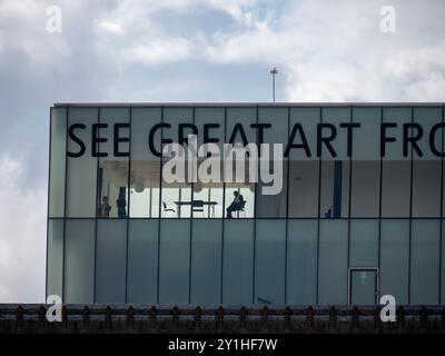 Tate Modern Art Gallery nel centro di Londra, dettagli dell'edificio con cartello SEE Great Art sul tetto e persona seduta in ufficio Foto Stock