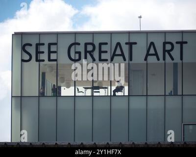 Tate Modern Art Gallery nel centro di Londra, dettagli dell'edificio con cartello SEE Great Art sul tetto e persona seduta in ufficio Foto Stock