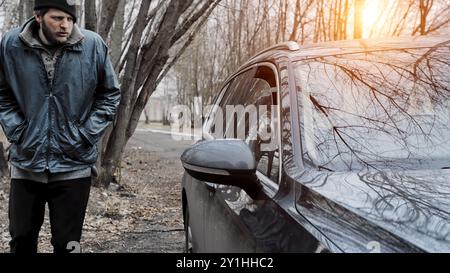 Maschio ladro burglar passando da sciocchi attraverso la crepa nella finestra di parcheggio auto vuoto, egli apre la porta sbloccata, tira denaro in contanti o smartphone o portafoglio, Foto Stock