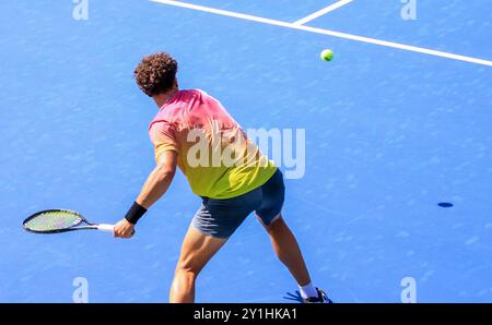 Vista posteriore di un tennista che oscilla aggressivamente con una forte prima mano, Foto Stock