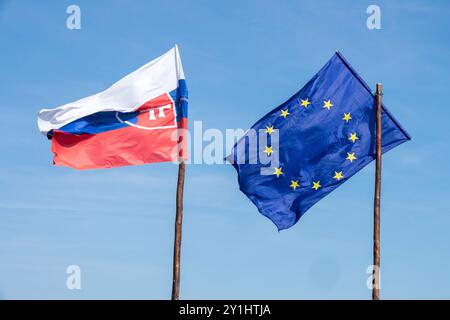 Bandiera della Slovacchia e bandiera dell'Unione europea che soffia nel vento su bandiere a palo di legno Foto Stock