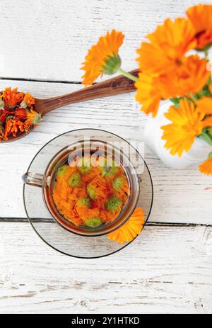 Calendula officinalis il vaso calendula, cornetti, calendula comune o calendula scozzese, pianta fiore tè a base di erbe in vetro trasparente, concetto di rimedio medico. Foto Stock