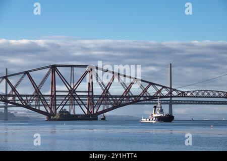 Tugboat che passa sotto Forth Bridge con Parallel Cloud Formation in Scozia Foto Stock