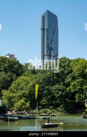 Barche a remi sul lago a Central Park con un nuovo edificio condominiale sul lato ovest sullo sfondo, estate 2024, New York City, Stati Uniti Foto Stock