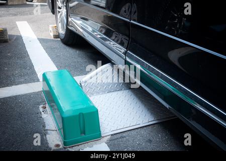 Serratura con ruote in metallo sotto un'auto nel parcheggio a pagamento in giappone Foto Stock