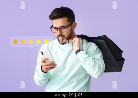 Giovane che dà una valutazione a una nuova applicazione mobile su sfondo lilla Foto Stock