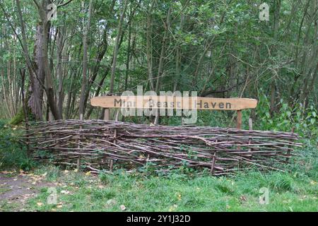 Cartello Mini Beast Haven a Thornham Walks, parte della Thornham Estate nel Suffolk, sopra una recinzione a ostacoli. Foto Stock