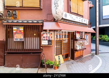 Tipico ristorante giapponese all'angolo di una strada nell'area di Kabukichō a Shinjuku. Lanterna sopra l'entrata e tradizionale porta scorrevole in legno. Foto Stock