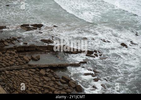 Onde marine e formazioni rocciose nel flysch vicino a Bilbao, nei Paesi baschi (Spagna). Foto scattata subito dopo la pioggia, con il mare agitato in una vittoria Foto Stock