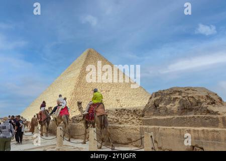 Il complesso piramidale di Giza, noto anche come necropoli di Giza, il Cairo, Egitto. Turisti che cavalcano i cammelli. Foto Stock