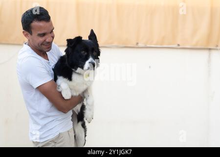 Un uomo ha un cane bianco e nero. Il cane sta indossando un collare giallo Foto Stock