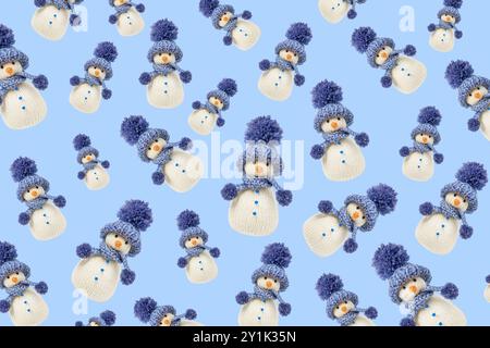 Favoloso modello natalizio di pupazzi di neve lavorati a maglia su sfondo blu. Fiaba invernale con le tue mani, hobby. Buon Natale e biglietto di auguri di Capodanno 2025 Foto Stock