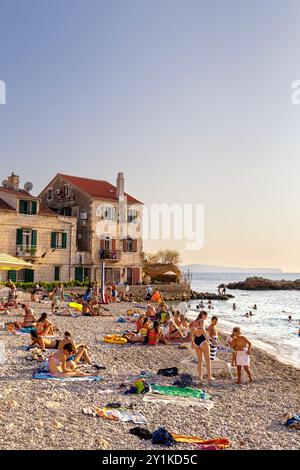 Persone che nuotano e prendono il sole sulla spiaggia di Komiza, Komiza, isola di Vis, Croazia Foto Stock