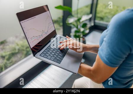 Donna professionista che lavora diligentemente su un notebook con diversi grafici della Borsa Foto Stock