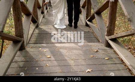 Gli sposi sposi scendono i gradini. Il primo passo nella vita familiare. I piedi della sposa e dello sposo camminano lungo i gradini di legno. Sposa e sposo. Foto Stock