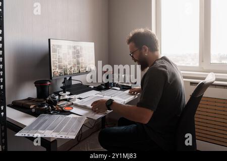 Fotografo che rivede i negativi cinematografici con la luce della finestra Foto Stock