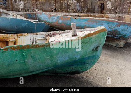 Vecchie barche a remi in legno, intemperie, non più in servizio, dipinte in blu e verde. Foto Stock