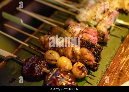 Yakitori, un tipo giapponese di pollo spiedato, manzo, maiale con vari tipi di funghi Foto Stock