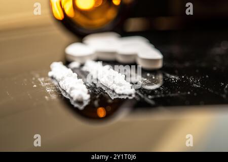 Polvere di fentanil e pillole di prescrizione sparse su una superficie riflettente, illustrando i gravi effetti dell'abuso di oppioidi e del farmaco da prescrizione abus Foto Stock