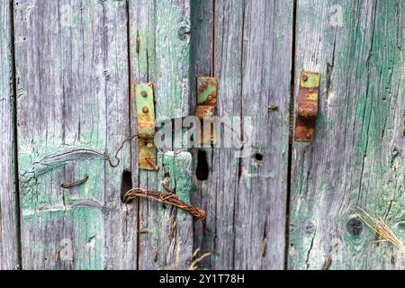 il tempo passato era sbiadito e sbiadito su una porta in legno verniciato verde con vecchia serratura arrugginita e maniglia in uno stile rustico elegante e shabby Foto Stock