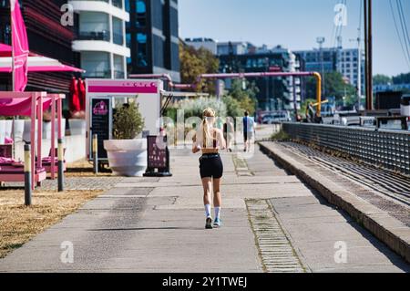 Berlino, Germania. 8 settembre 2024. Una donna cammina lungo la Sprea a tarda estate nell'Osthafen. Crediti: Paul Zinken/dpa/Alamy Live News Foto Stock