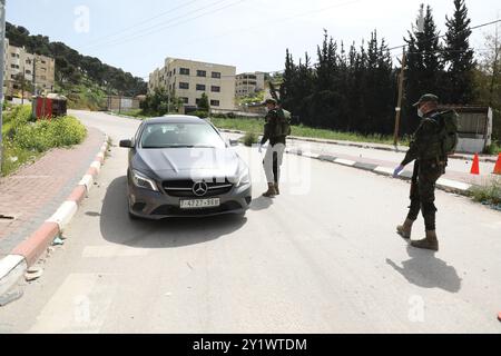 Jenin, West Bank. 23 marzo 2020. I membri delle forze di sicurezza nazionali palestinesi hanno istituito una barriera e svolgono controlli all'ingresso della città di Jenin per far rispettare l'attuazione di nuove misure restrittive contro la diffusione del coronavirus in Cisgiordania. Domenica il primo ministro palestinese ha ordinato un divieto di due settimane su tutti i movimenti non essenziali per contenere la diffusione del COVID-19, mentre il numero di casi confermati in Cisgiordania è salito a 57 Foto Stock