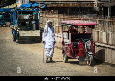 Abhaneri Village, India - 13 aprile 2023. Un anziano indiano cammina con veicoli parcheggiati sul lato della strada nel villaggio di Abhaneri. Foto Stock